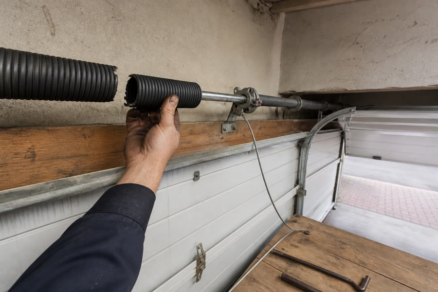 Snapped torsion spring on the header shaft, winding bars on the bench, sectional door clamped open.